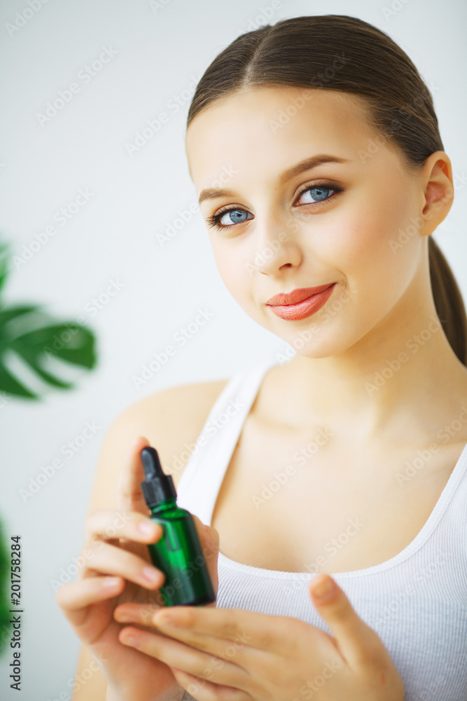 Portrait of a young smiling woman holding a green bottle with cosmetics Portrait of a young smiling woman holding a green bottle with cosmetics