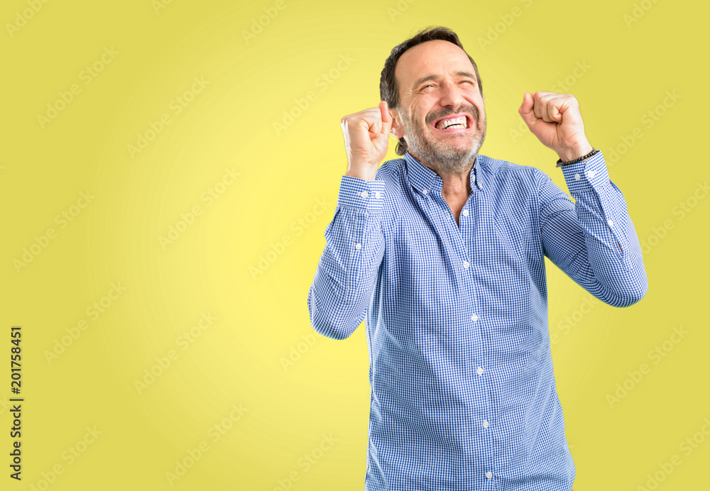 Handsome middle age man happy and excited expressing winning gesture. Successful and celebrating victory, triumphant Handsome middle age man happy and excited expressing winning gesture. Successful and celebrating victory, triumphant