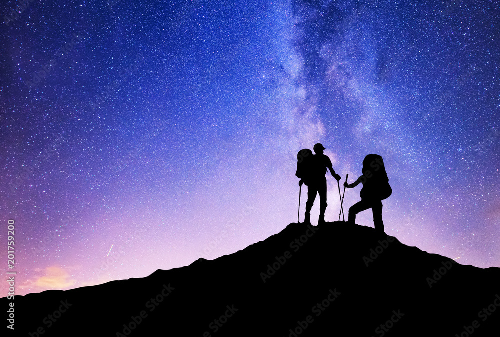 Silhouettes of team on mountain peak. Sport and active life concept on the night sky background.