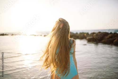 girl with beautiful hair covering face on beach at summer.