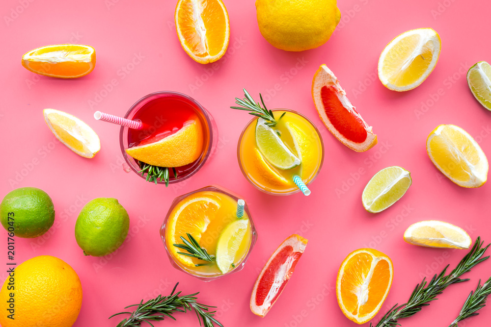 Tropical fruit cocktail with alcohol. Glass with beverage near oranges, grapefruit, lime and rosemary on pink background top view pattern Tropical fruit cocktail with alcohol. Glass with beverage near oranges, grapefruit, lime and rosemary on pink background top view pattern