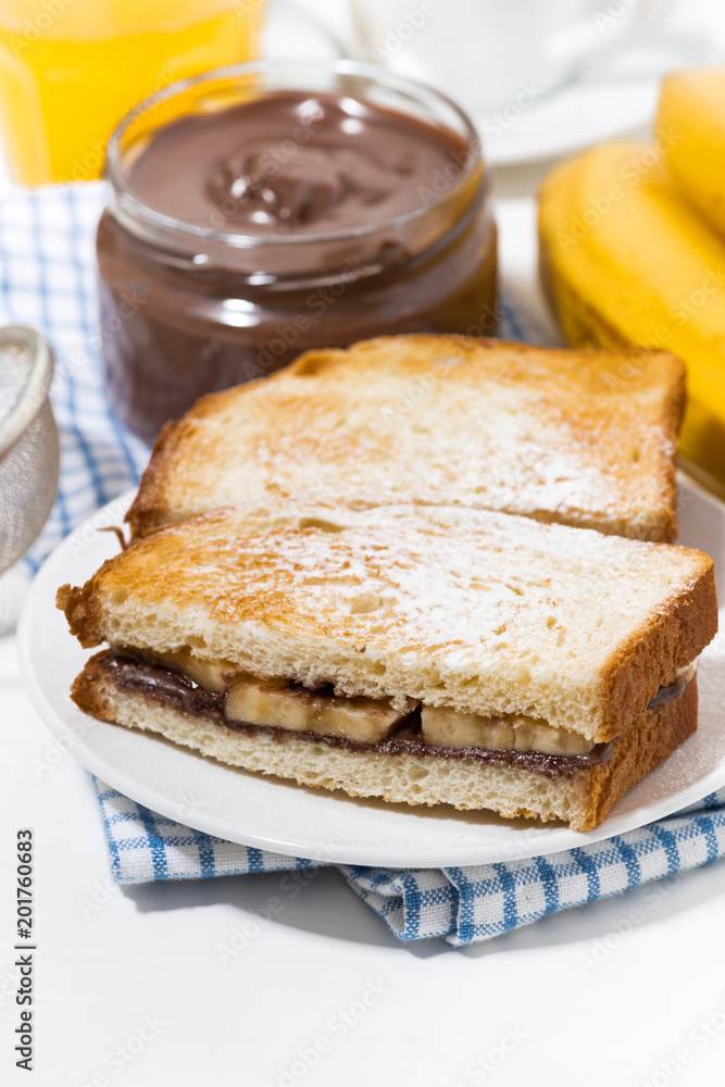 sweet sandwich with chocolate paste and banana for breakfast, vertical closeup