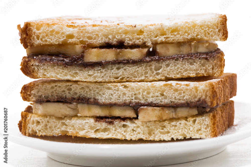 sweet sandwich with chocolate paste and banana on white plate, closeup sweet sandwich with chocolate paste and banana on white plate, closeup