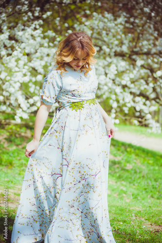 Beautiful pregnant woman walking in the flowers garden in the spring