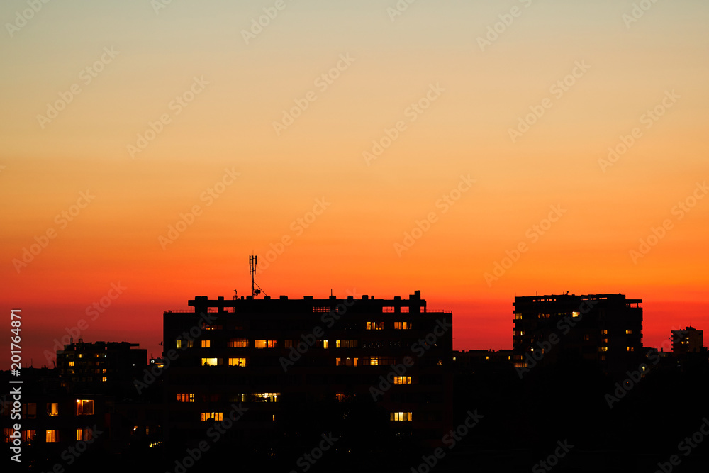 Bright sunset over an evening city. Bright lights of high buildings of urban residents