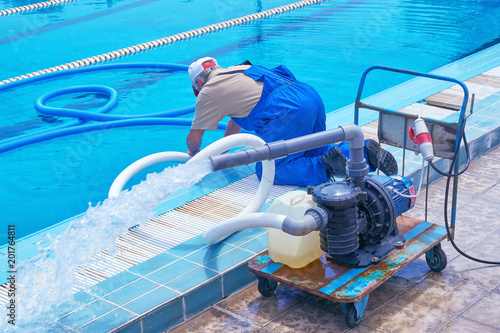 The worker in overalls makes cleaning of the sports urban pool. Cleaning systems for swimming pools. Personnel cleaning                          