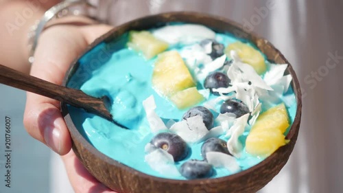 hands holding blue majik smoothie bowl approaching camera lens photo