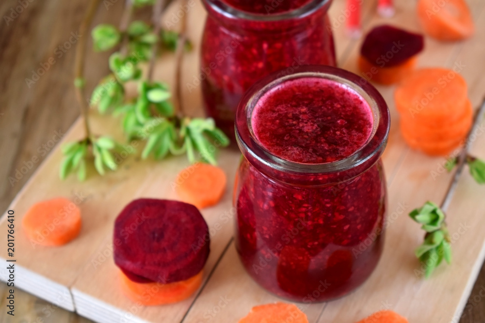 Red vegetable smoothie made of carrot and beetroot in glass jars on wooden background Red vegetable smoothie made of carrot and beetroot in glass jars on wooden background