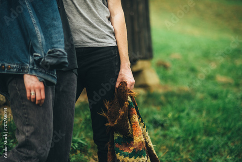couple in jeans is holding colored rug in the mountains