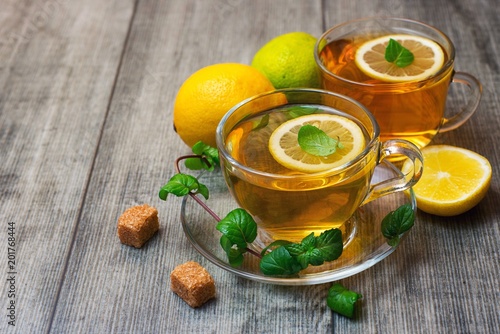 Two Glass tea Cup's with lemon, lime and mint on grey wooden background