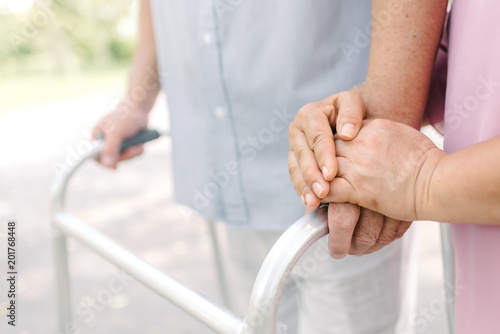 Hand of senior couple using walker in park