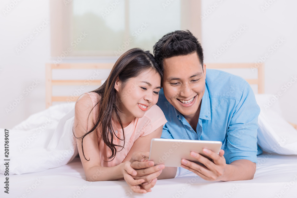 Asian couple using digital tablet on the bed Asian couple using digital tablet on the bed
