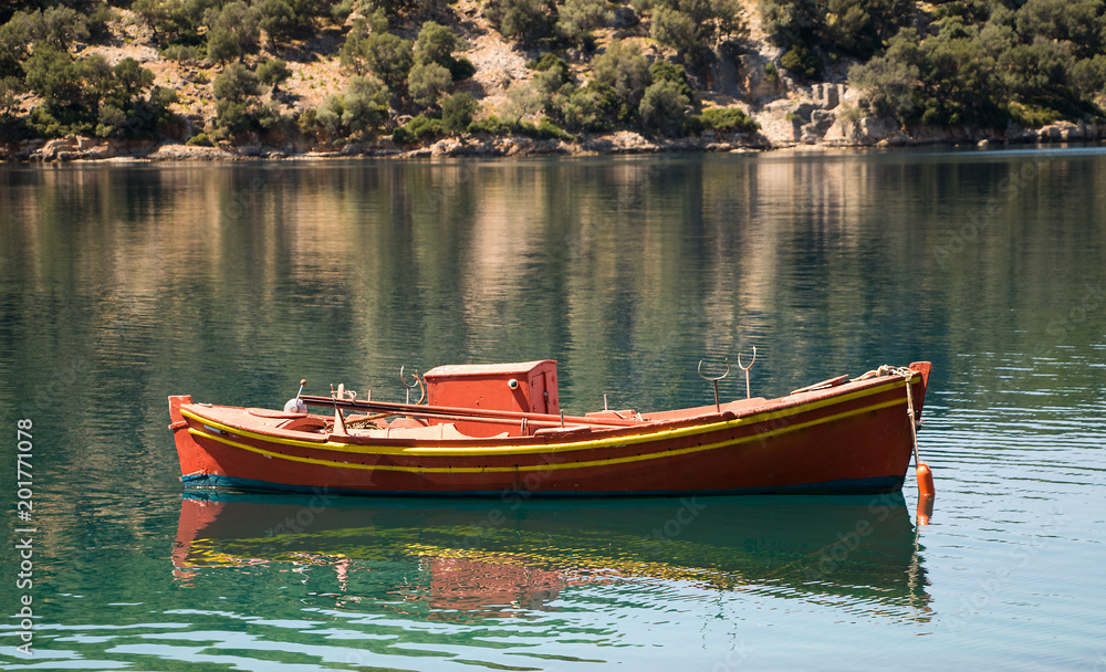 Vorsaison am Mittelmeer mit traditionellen griechischen Fischerboot und spiegelglatten Meer