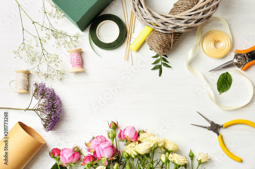 Florist equipment with flowers on wooden background, top view photo