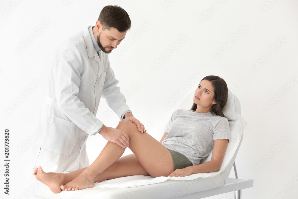 Doctor examining female patient with injured leg in clinic Doctor examining female patient with injured leg in clinic