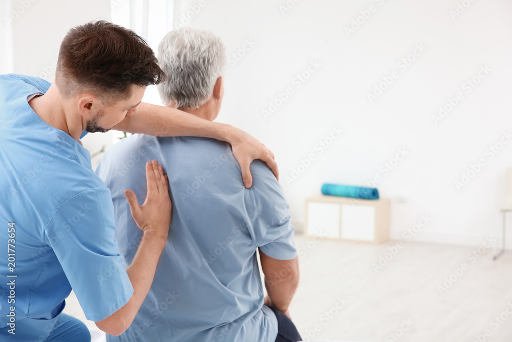 Fototapeta premium Young physiotherapist working with senior patient in clinic