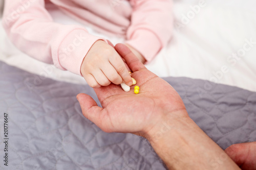 Recovery. Little sick girl having a flu and taking pills from her daddys palm
