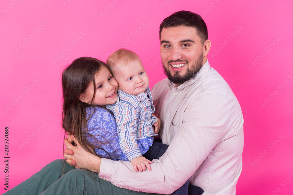 handsome father carrying his little daughter and baby son on pink background handsome father carrying his little daughter and baby son on pink background