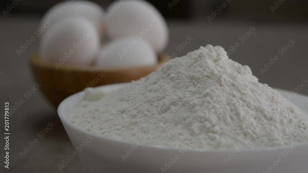 camera moves the focus from flour to white eggs camera moves the focus from flour to white eggs