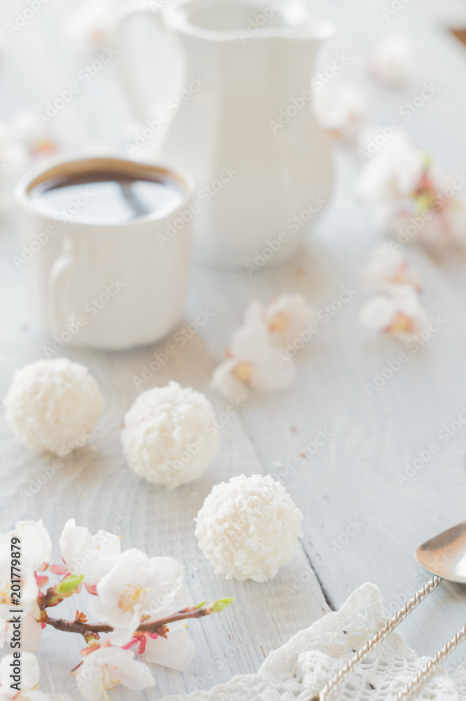 Cup of coffee, milk and apricot blossoming branch on white wooden table Cup of coffee, milk and apricot blossoming branch on white wooden table