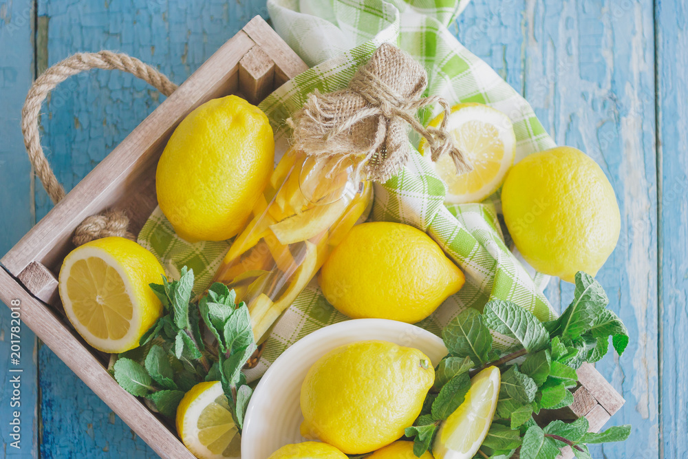 Yellow lemons with mint leaves in the wooden tray
