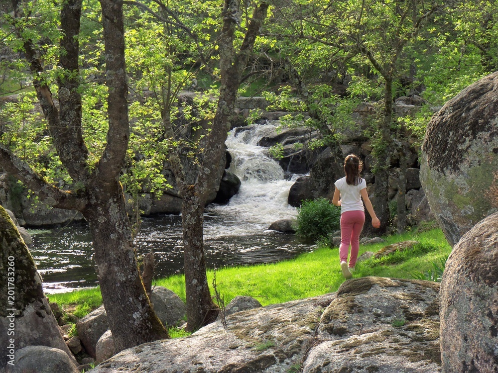 Niña pequeña caminando hacia el río. Niña en el bosque