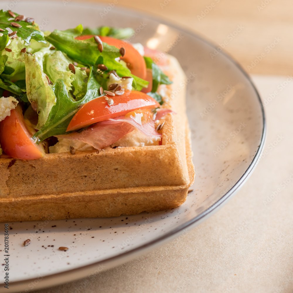 Savory Belgian waffles with salmon, salad and tomato. Perfect breakfast for long day. Restaurant menu or recipe concept Savory Belgian waffles with salmon, salad and tomato. Perfect breakfast for long day. Restaurant menu or recipe concept