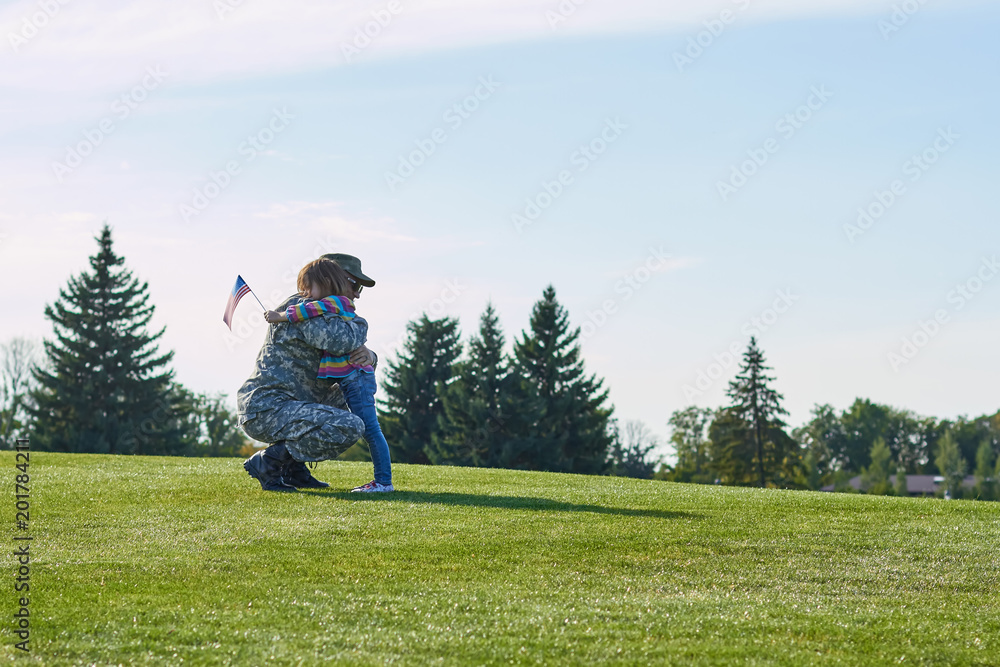 Soldier is hugging with his little daughter outdoor. Happy child is meeting her military father in the summer park. Soldier is hugging with his little daughter outdoor. Happy child is meeting her military father in the summer park.