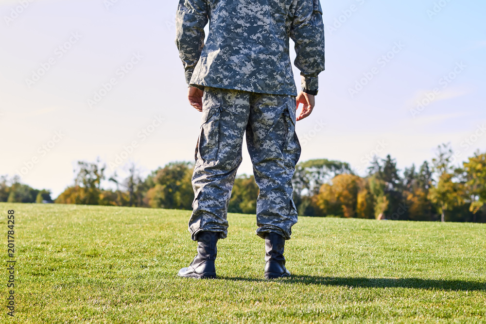 Soldier on the grass, back view. Man in camouflage on the sunny summer park meadow. Soldier on the grass, back view. Man in camouflage on the sunny summer park meadow.