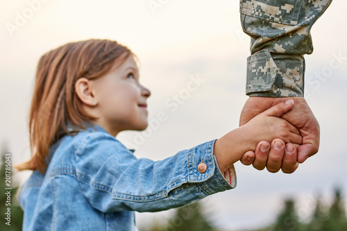 Soldier holding hand of little girl, close up. Hands of father and daughter.