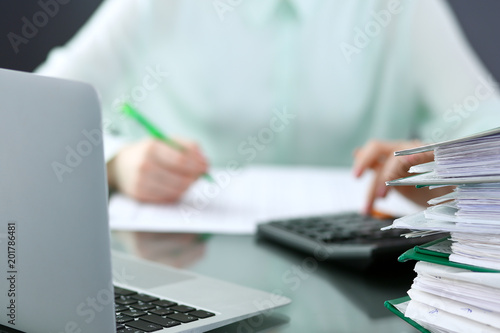 Bookkeeper or financial inspector making report, calculating or checking balance. Binders with papers closeup. Audit and tax service concept. Green colored image background 