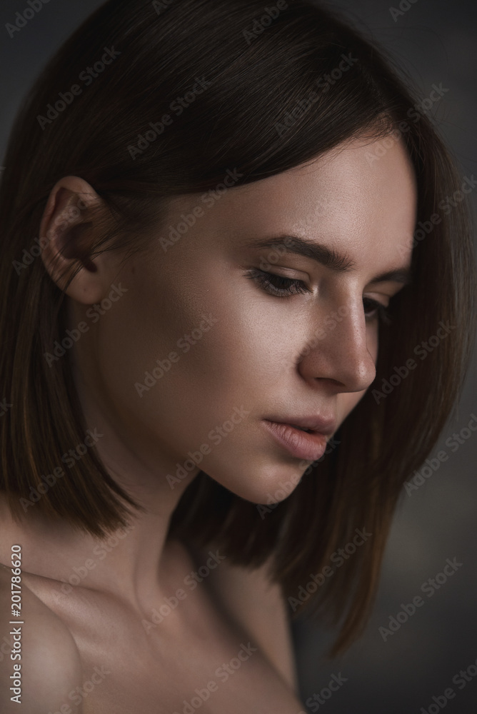 Dramatic portrait of a young beautiful brunette woman with short haircut in the studio. Dramatic portrait of a young beautiful brunette woman with short haircut in the studio.