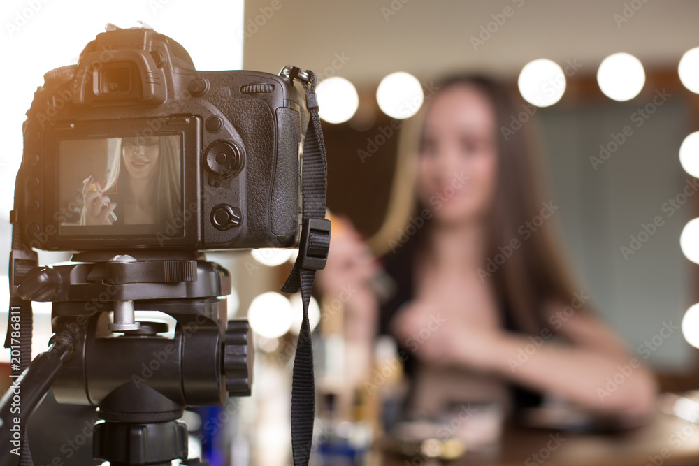 Beauty blog. Close up of professional camera screen is showing the recording video with charming young female blogger. Selective focus