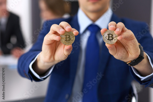 Businessman holding golden bitcoin and smiling. Virtual anonymous money concept, success in digital finance