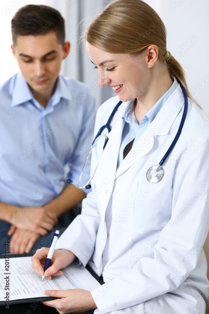Female doctor holding application form while consulting man patient in hospital office. Medicine and healthcare concept Female doctor holding application form while consulting man patient in hospital office. Medicine and healthcare concept