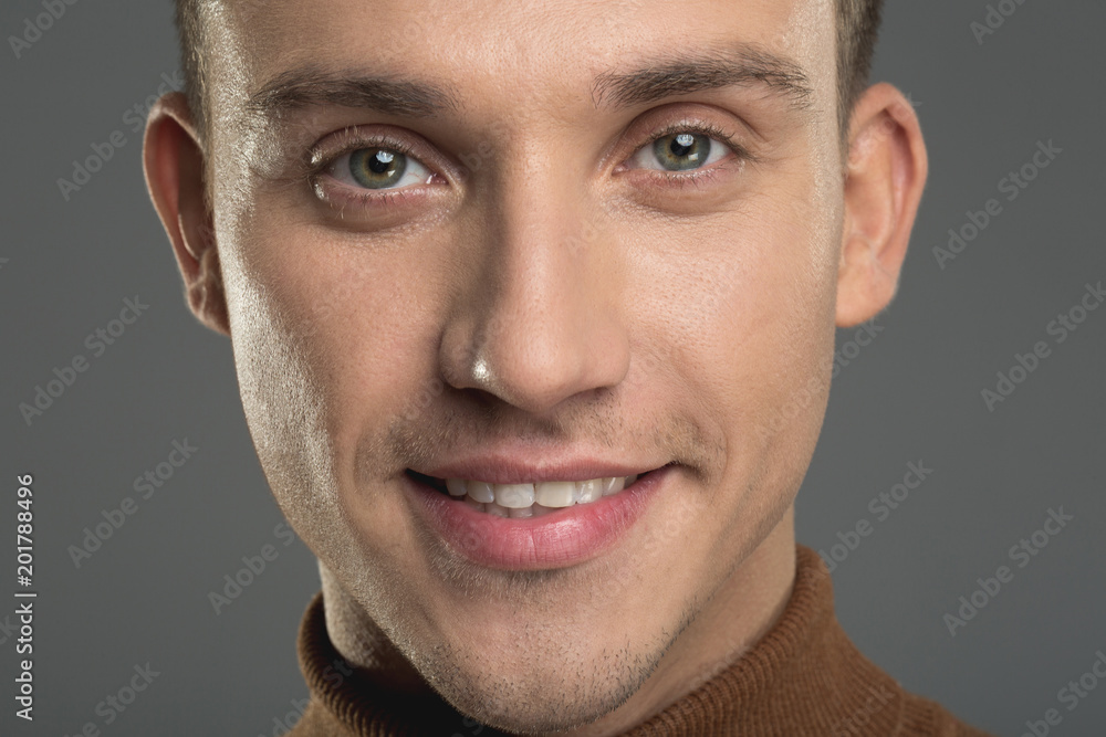 Fototapeta premium Close up of glad male face with soft skin and green eyes. Isolated on background