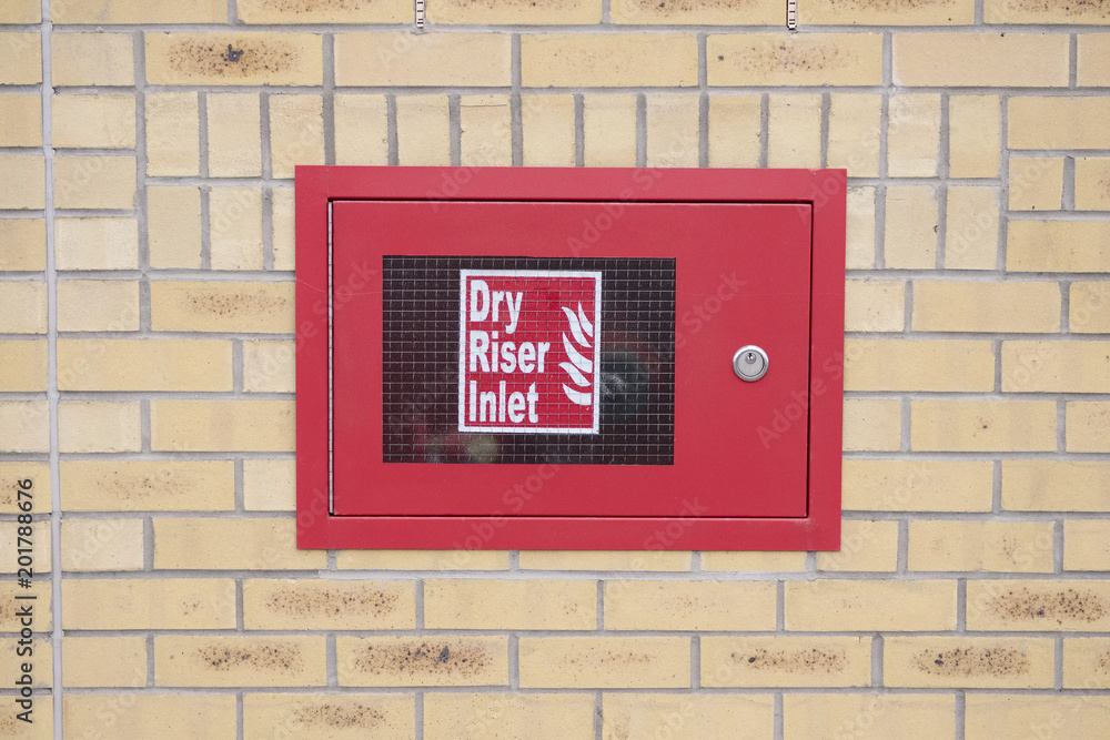 Dry riser inlet box red on brick wall for emergency fire services water