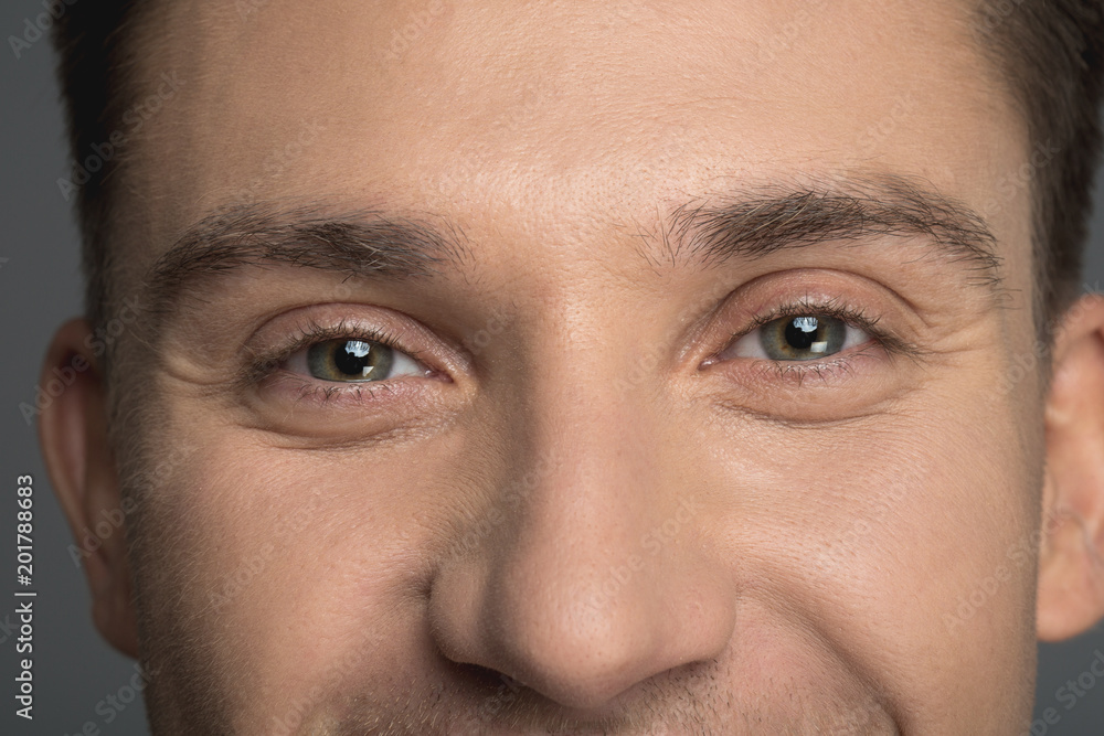 Close up of male light eyes staring at camera. Man is smiling Close up of male light eyes staring at camera. Man is smiling