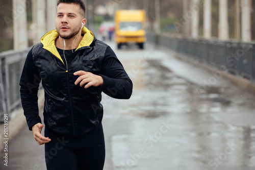 Sports man jogging on the bridge in rainy day