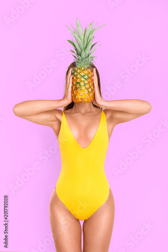Sexy girl in a yellow bathing suit with a pineapple on a pink background
