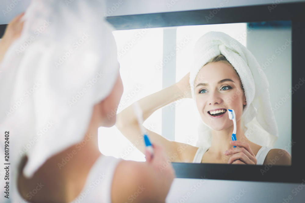 Young woman looking in mirror after brushing teeth Young woman looking in mirror after brushing teeth
