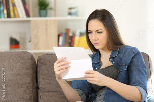 Worried woman reading a letter at home