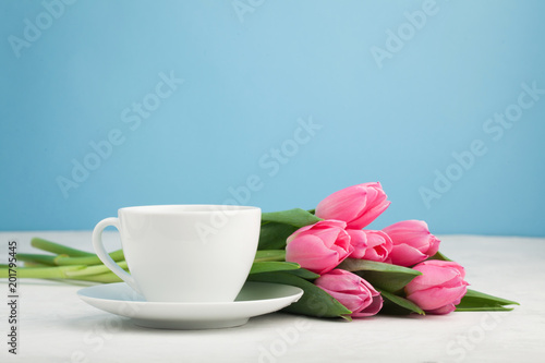 Black coffee in white Cup with pink tulips on light stone background