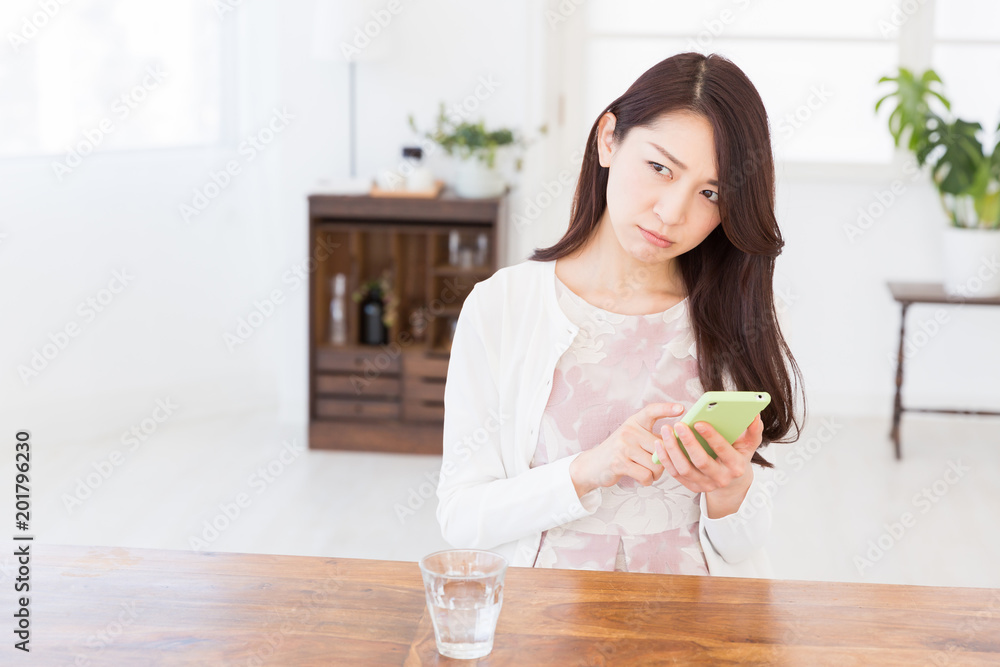 部屋でスマホを見る女性 考える 部屋でスマホを見る女性 考える