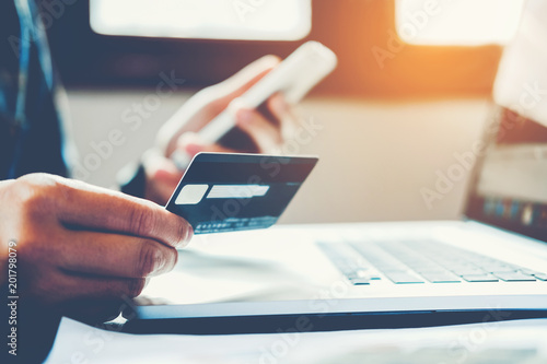 Man Holding Credit Card And Using Cell Phone holding credit card with shopping online photo
