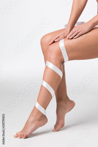 Women's legs with white ribbon