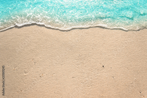 Fototapeta Soft waves with foam of blue ocean on the sandy beach