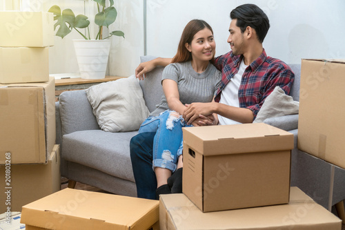 Asian young couple Sitting on the sofa for relax after success packing big cardboard box for moving in new house, Moving and House Hunting concept