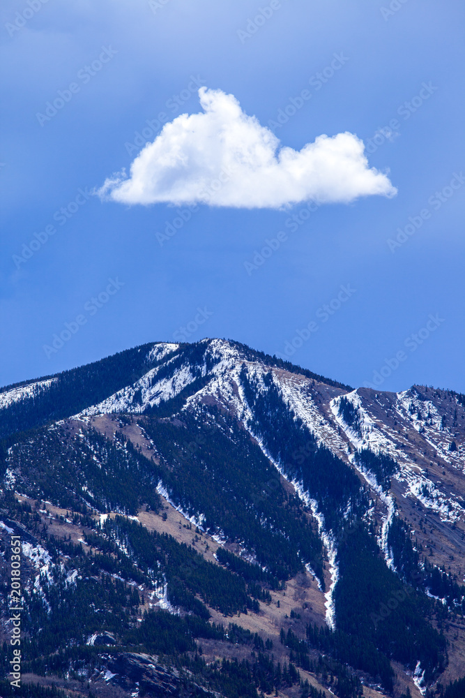 A single white cloud above a mountain peak