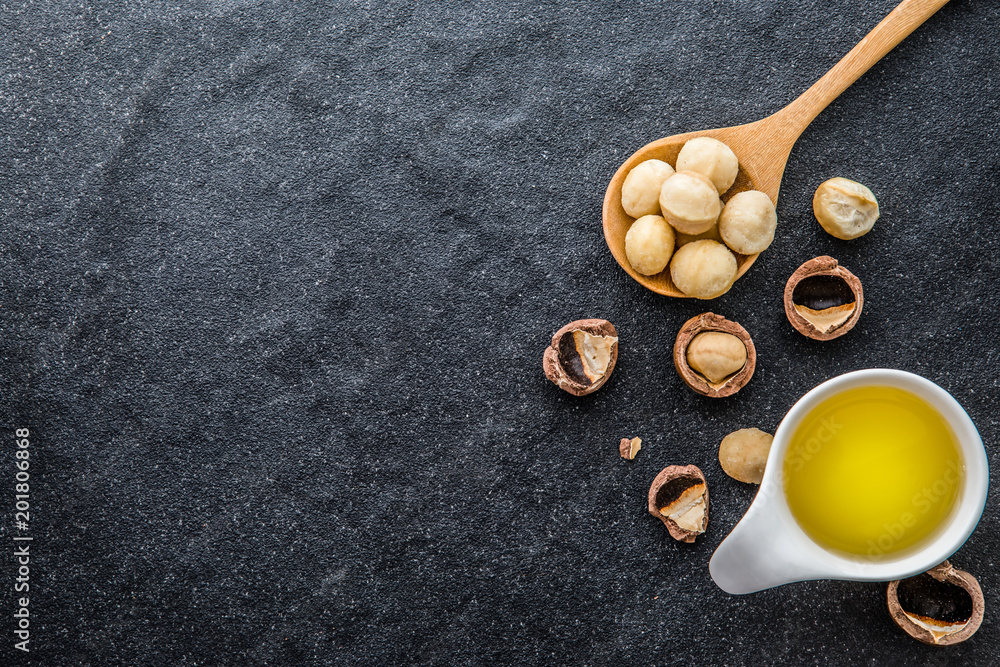 The Macadamia Nut Oil and peeled macadamia nut on black stone , use for Healthy Skin and Hair and Natural Healing Oil Treatment , overhead and top view The Macadamia Nut Oil and peeled macadamia nut on black stone , use for Healthy Skin and Hair and Natural Healing Oil Treatment , overhead and top view
